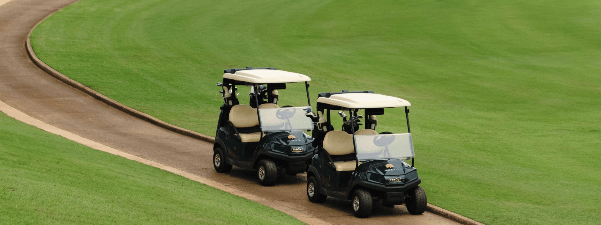 Two golf carts on a winding path through a lush green golf course.