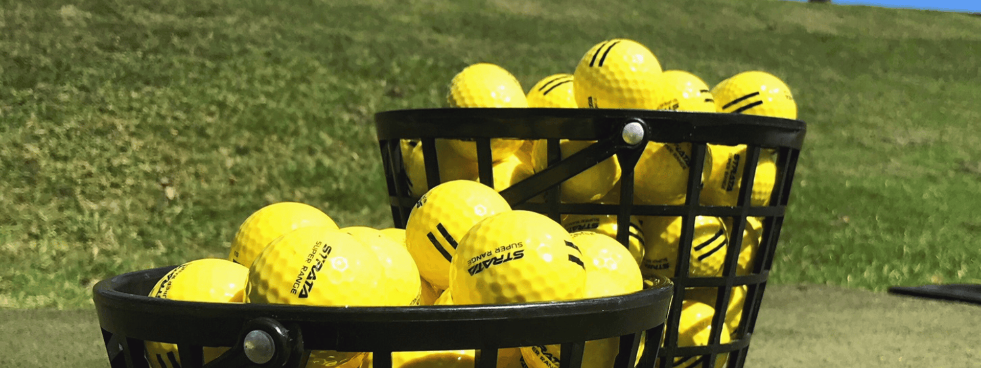 A basket filled with bright yellow golf balls on a grassy field.